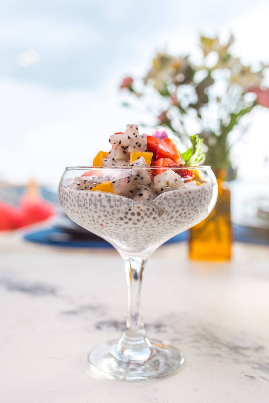 Chia seed pudding with fresh fruit in glass on white table with blurred background. Healthy eating, dieting, or detox concept.