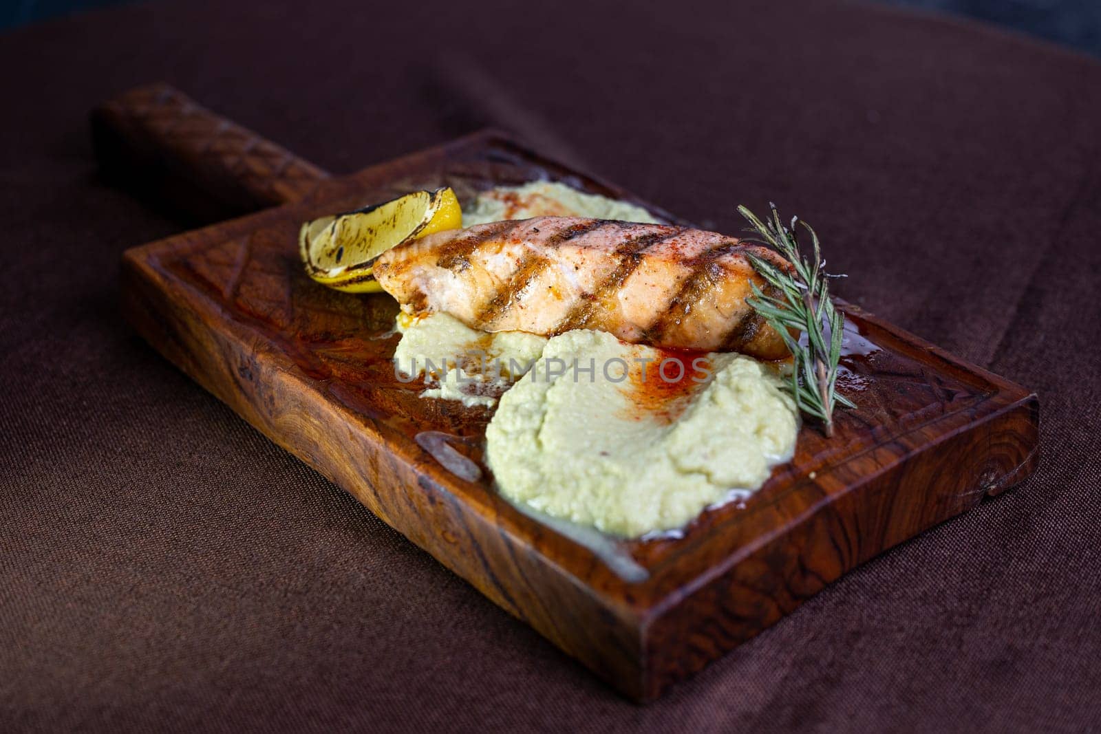 Grilled salmon fillet with lemon and herb butter on a wooden board by Pukhovskiy