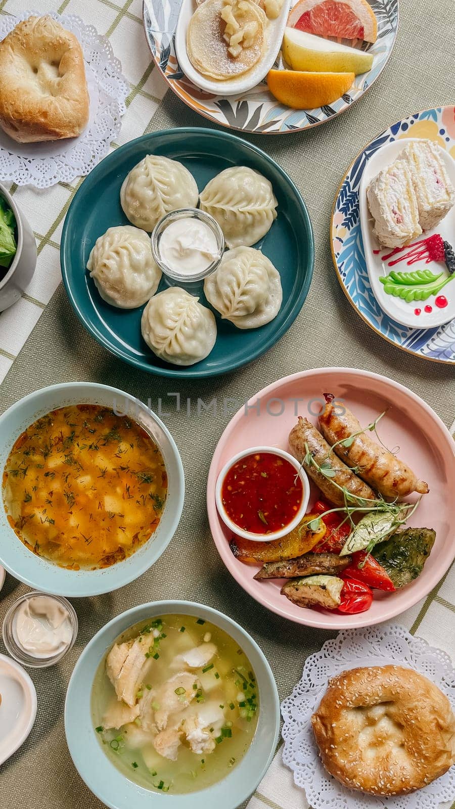 A variety of Uzbek Food on a table including dumplings, soup, salad, pastries, and bread with jam and butter.