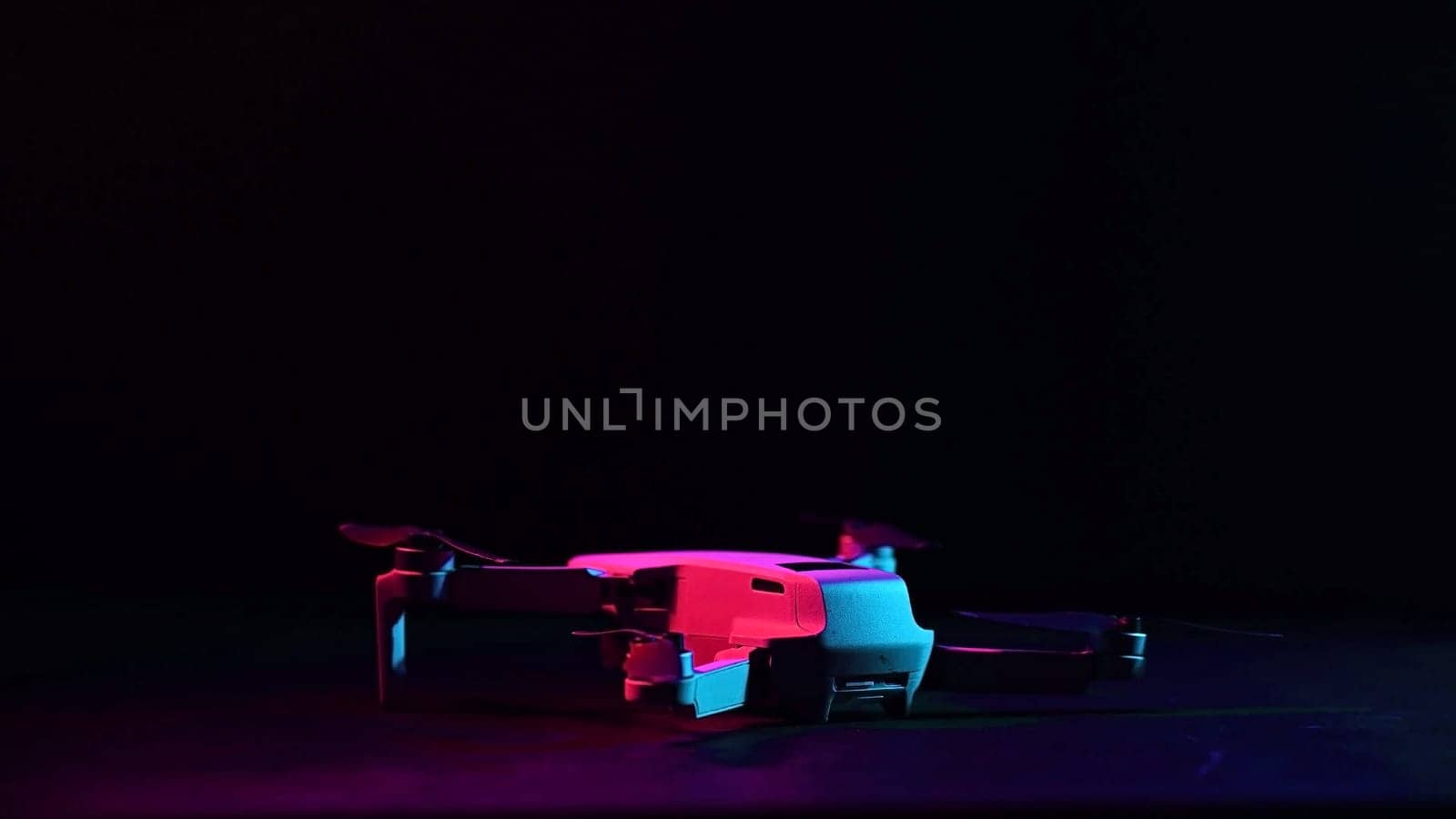 Quadrocopter in clouds of colored pink-blue smoke on a black background