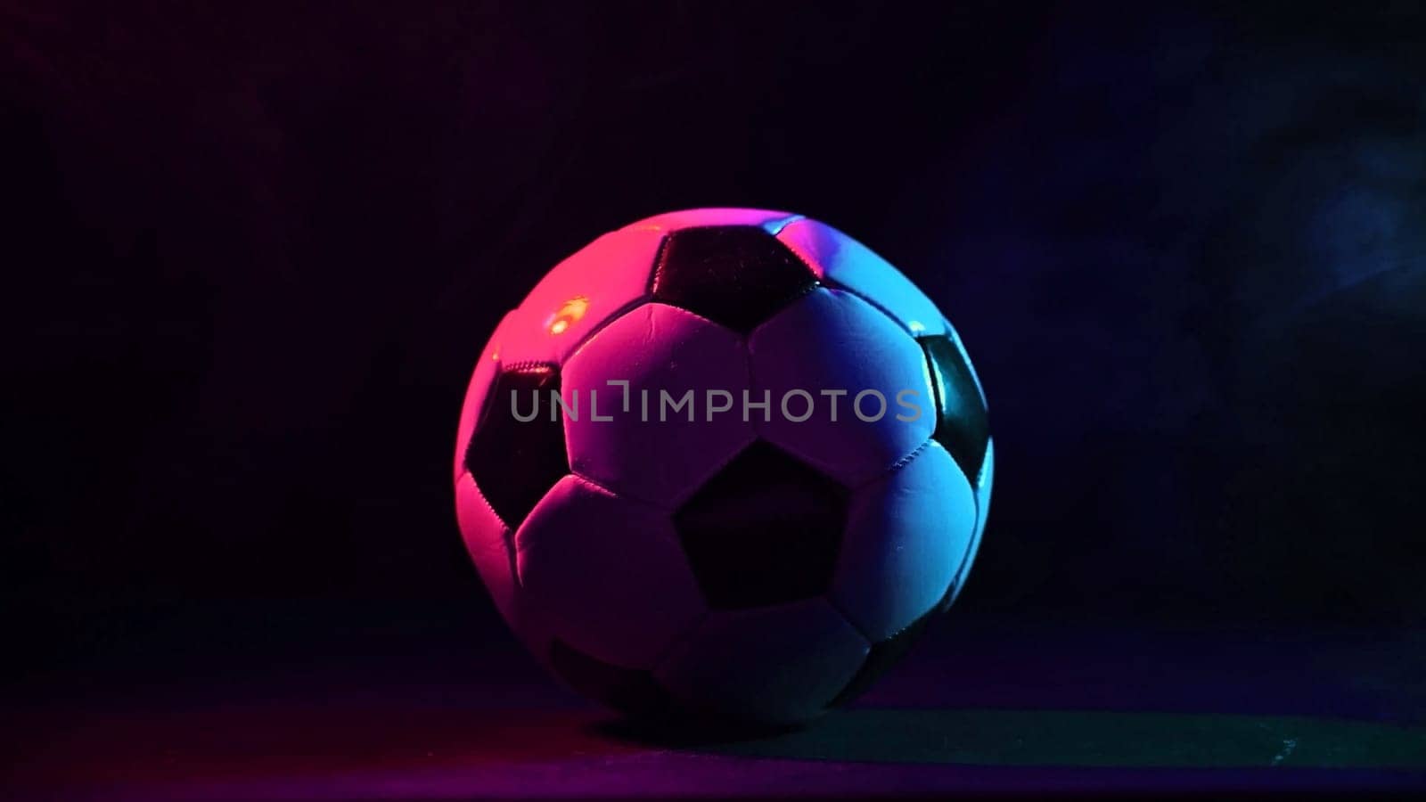 Soccer ball in blue pink smoke on black background