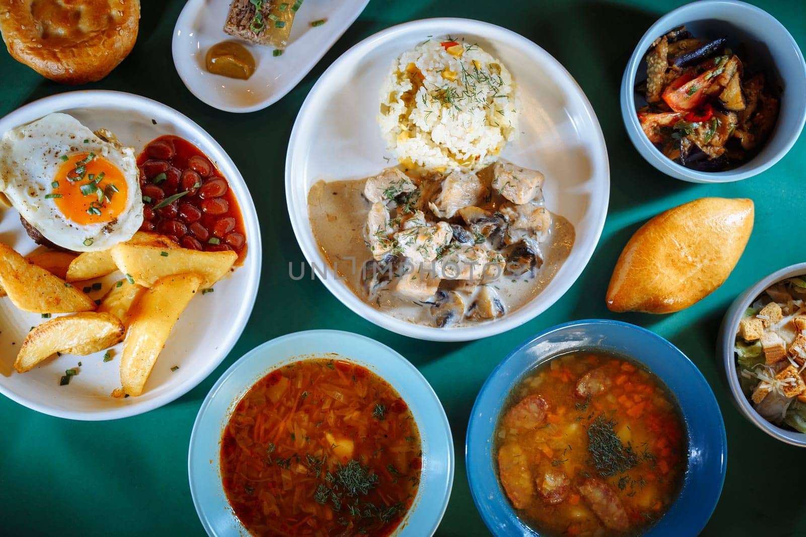 A variety of delicious and healthy food displayed on a green table. The spread features soups, salads, bread, and refreshing drinks.