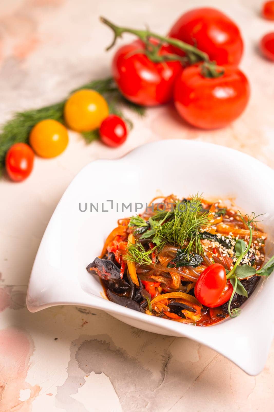 A delicious and healthy meal of Japchae, made with sweet potato noodles, vegetables, and a savory sauce, garnished with tomatoes and dill