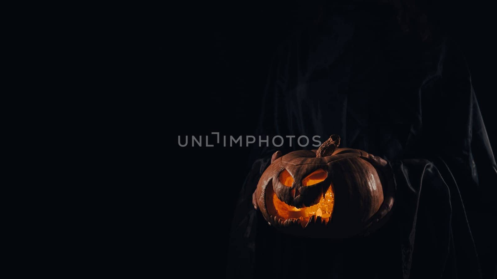 The witch is holding a pumpkin jack o lantern glowing in the dark. Halloween. by mrwed54