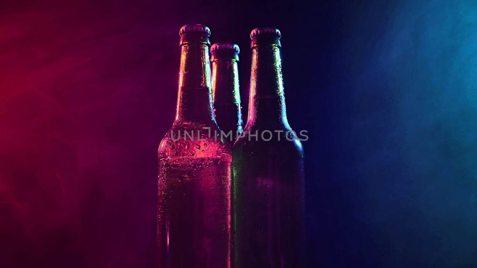 Three bottles of beer spinning in a blue-pink mist