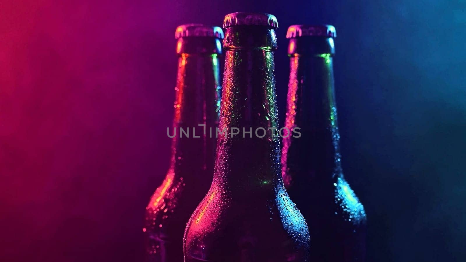 Three bottles of beer spinning in blue pink fog