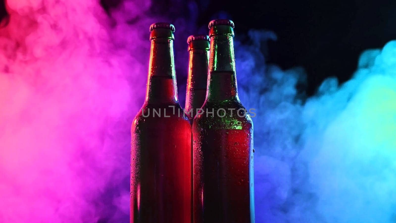 Three bottles of beer spinning in blue pink fog