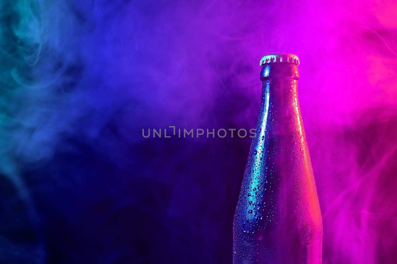 Glass bottle of beer in blue pink mist.