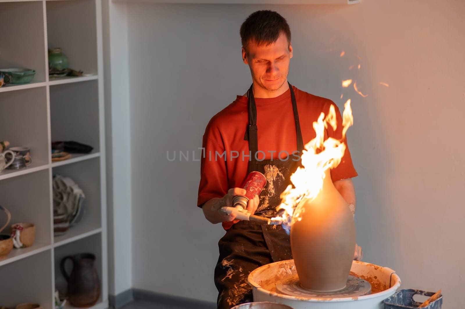 A potter burns a jug with a gas burner on a potter's wheel. by mrwed54