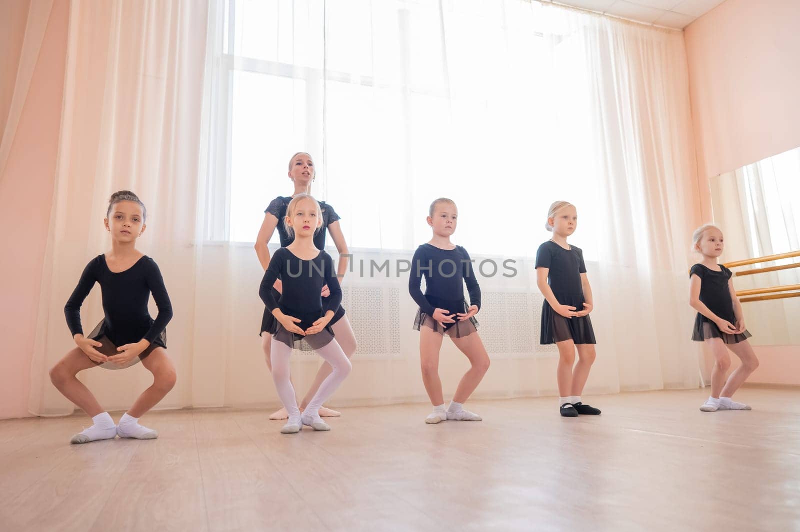 Children's ballet school. Caucasian woman teaching ballet to little girls