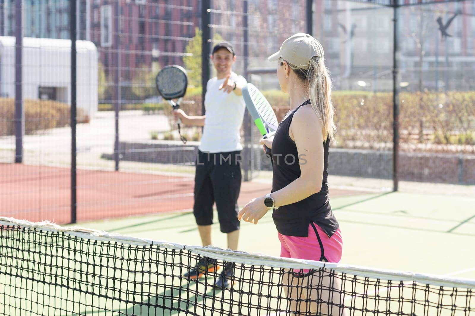 young woman playing Padel Tennis with partner in the open air tennis court by Andelov13