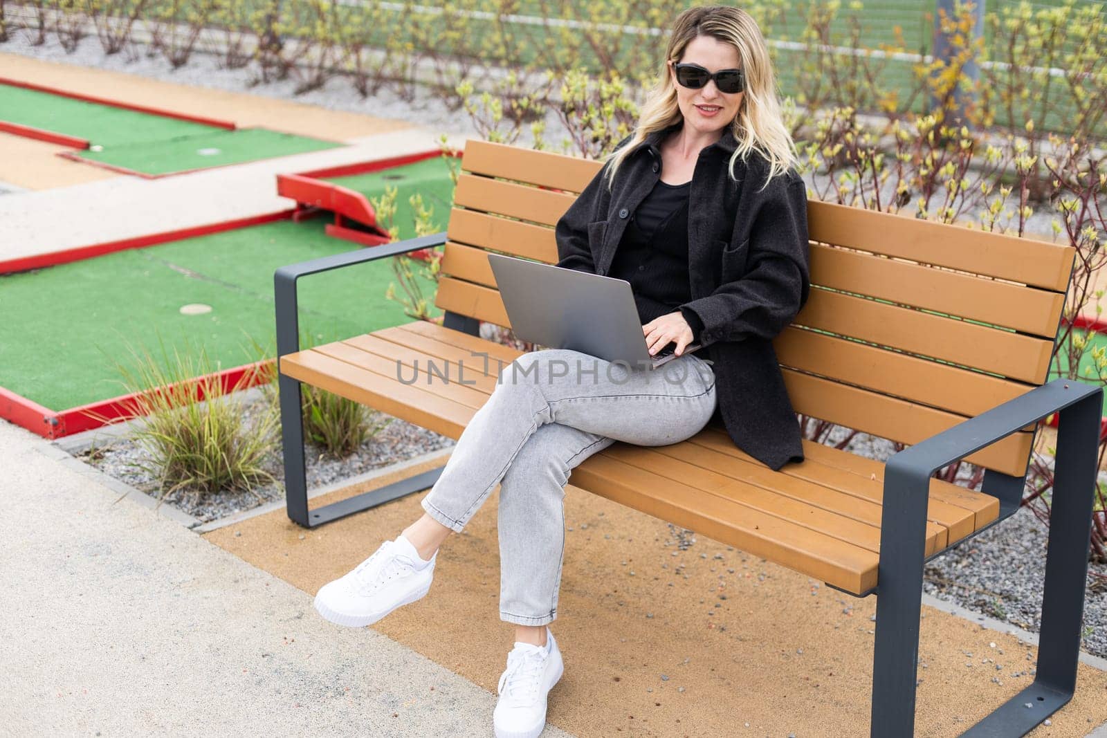 A businesswoman using a laptop on a golf course by Andelov13