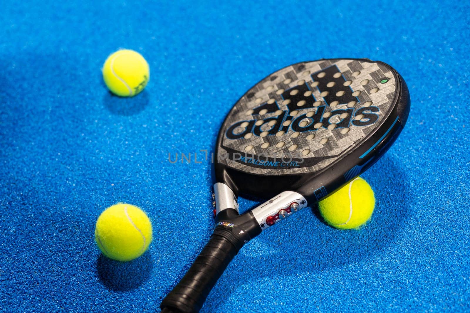 Kyiv, Ukraine, April 18, 2024. Black professional paddle tennis racket and ball with natural lighting on blue background. Horizontal sport theme poster, greeting cards, headers, website and app by Andelov13
