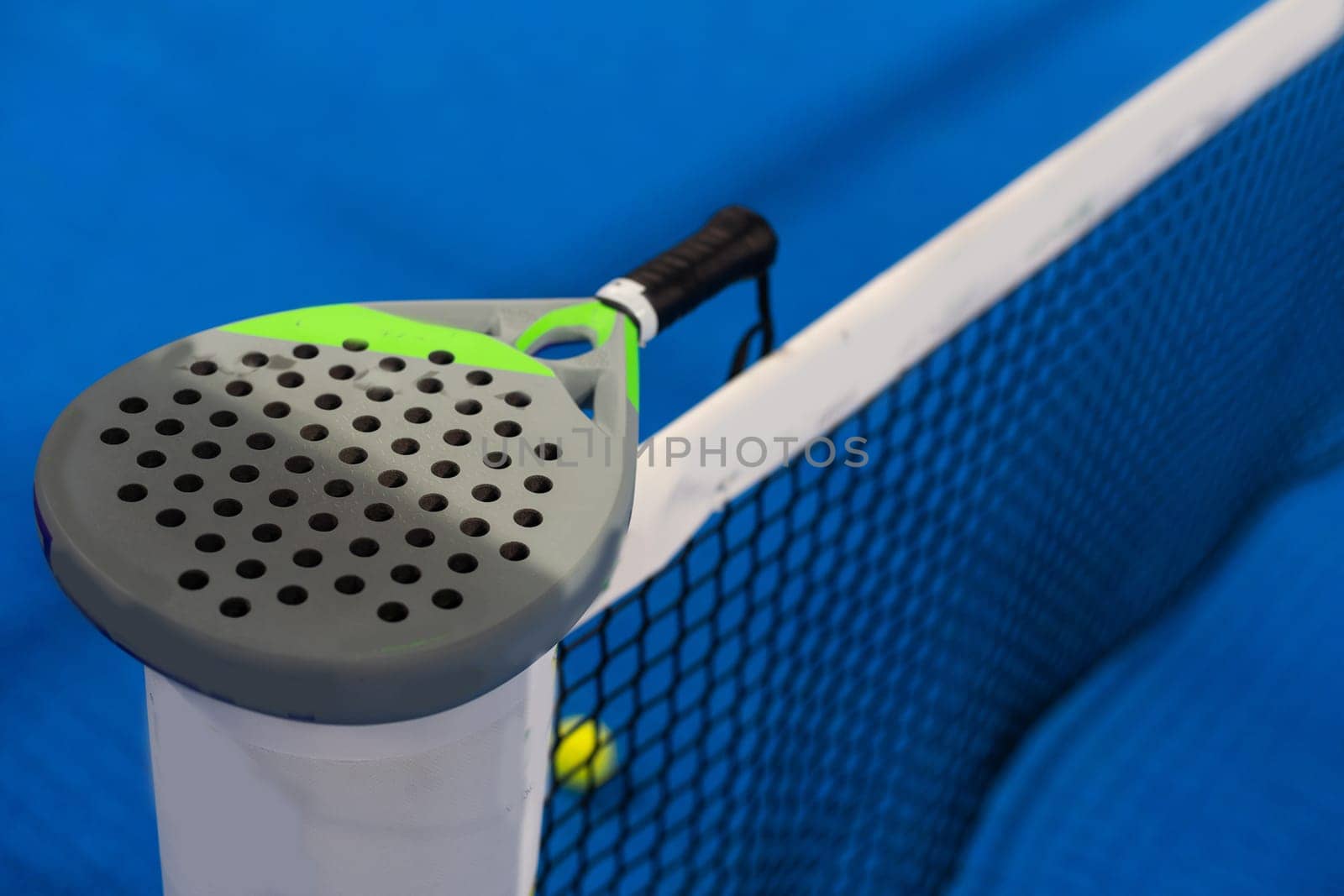 Twoo balls next to the net of a blue paddle tennis court. Sport healthy concept. High quality photo