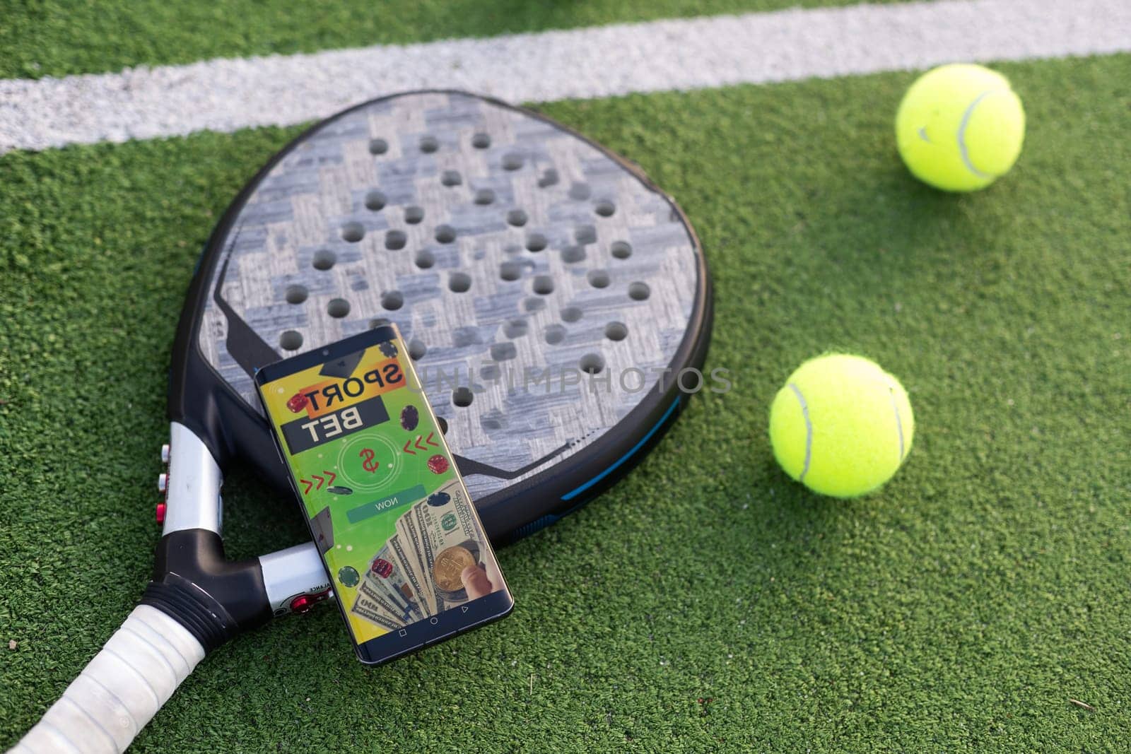 A tennis ball, a racket and a mobile phone with a put screen lie on a blue background. The concept of advertising a tennis club or ordering services. Horizontal photo by Andelov13