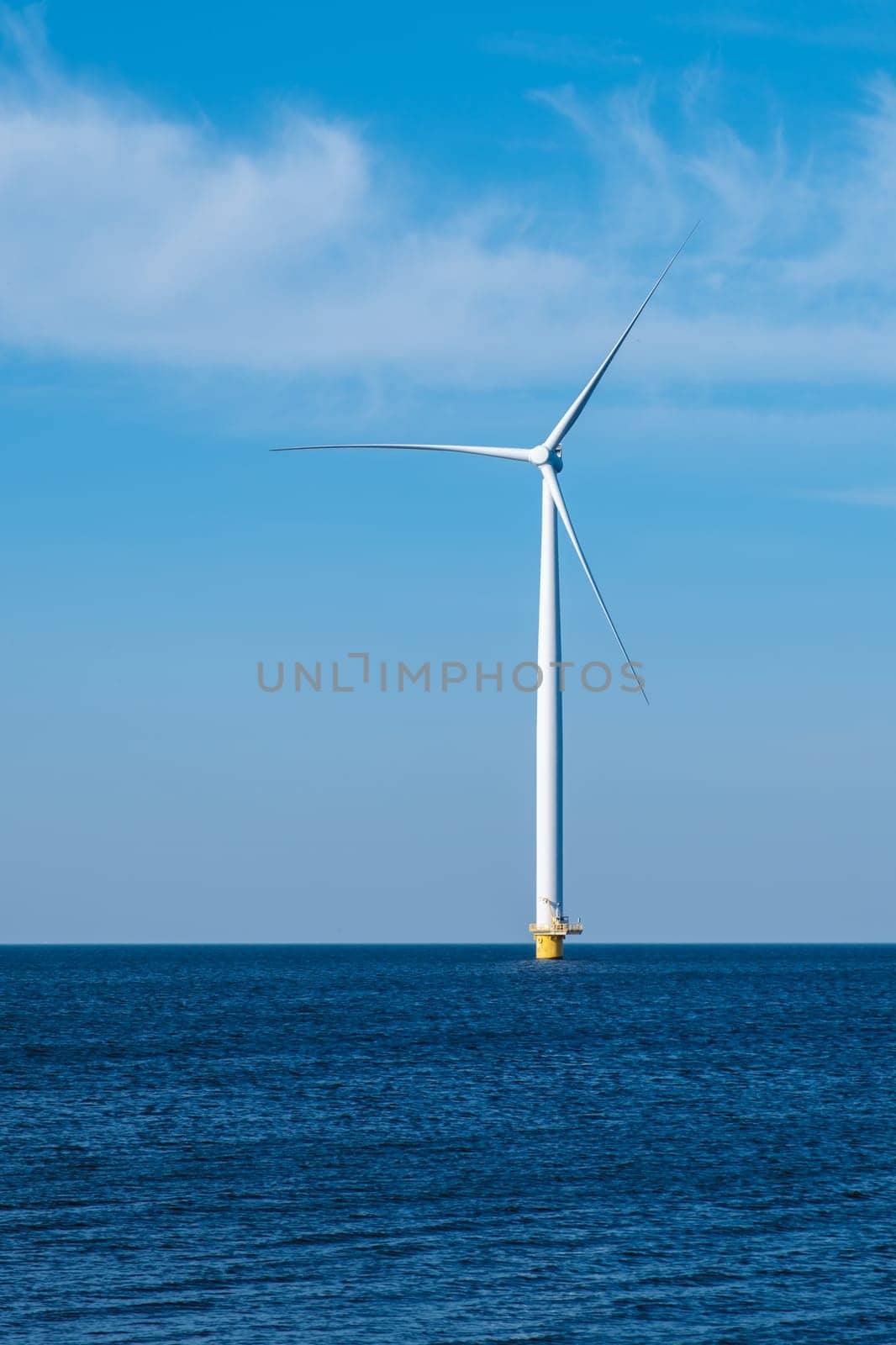 A solitary wind turbine stands tall in the vast ocean, harnessing the power of the wind to generate clean energy for a sustainable future by fokkebok