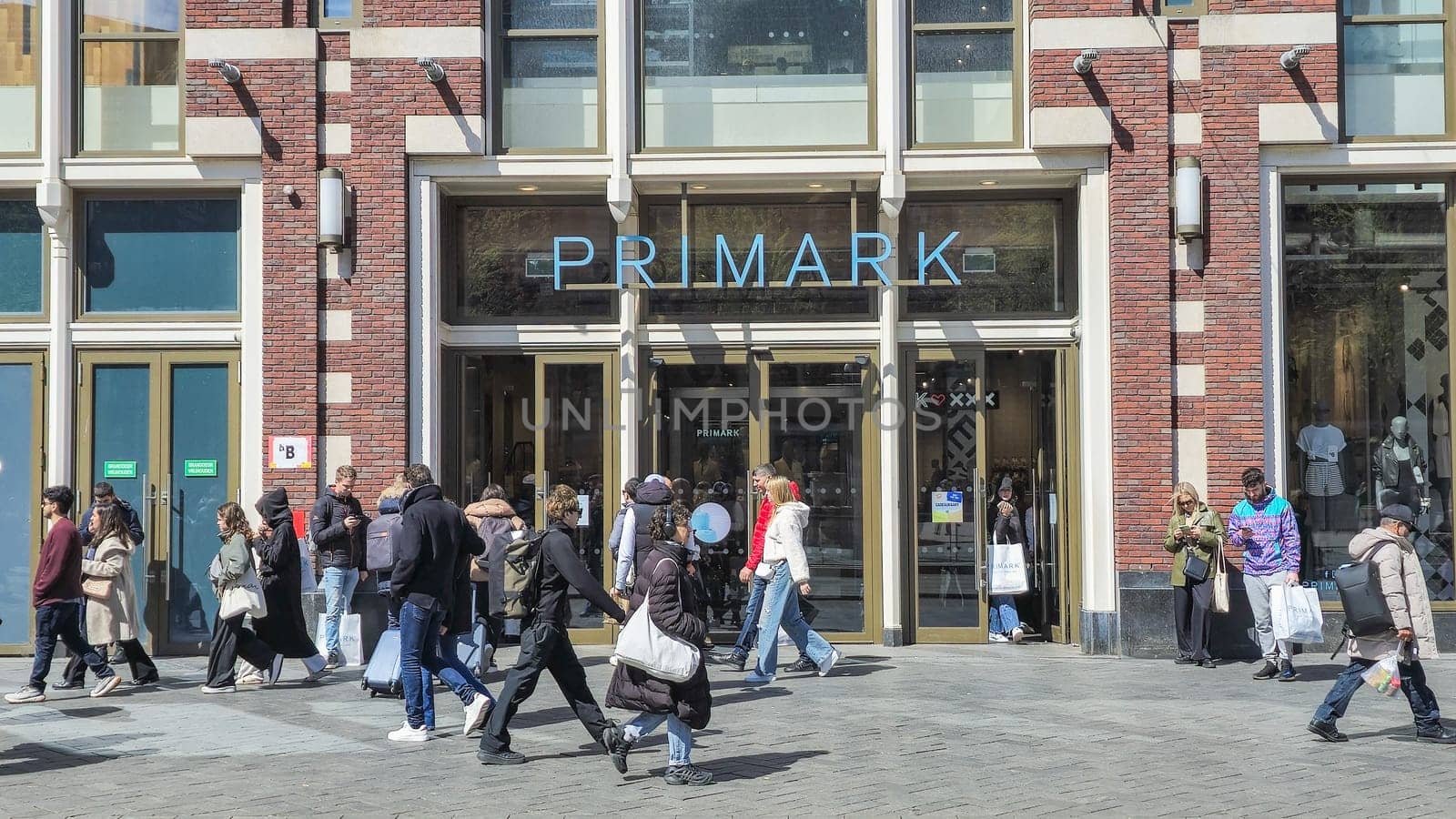 A diverse group of individuals walking gracefully in front of a Primark shop, each with their own unique style and pace by fokkebok