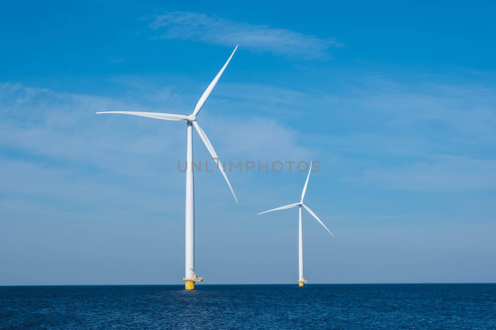 Three colossal wind turbines stand tall and majestic in the vast expanse of the ocean, harnessing the powerful energy of the wind to generate electricity. copy space, green energy in the Netherlands