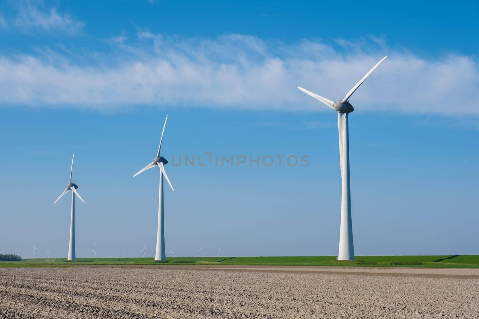 A majestic row of towering wind turbines spin gracefully in a vast field in Netherlands Flevoland, harnessing the power of the wind to generate clean, sustainable energy. Energy transition