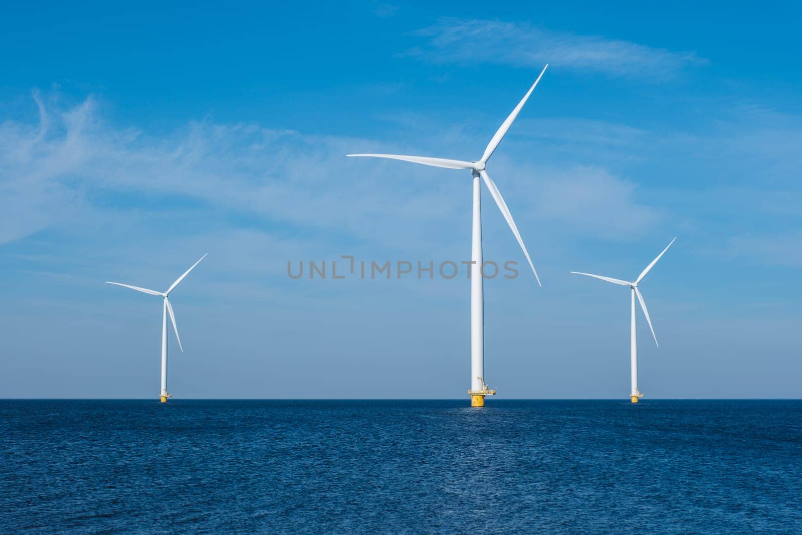 A group of elegant wind turbines stands tall in the ocean in the Netherlands Flevoland, harnessing the power of the wind to generate renewable energy by fokkebok
