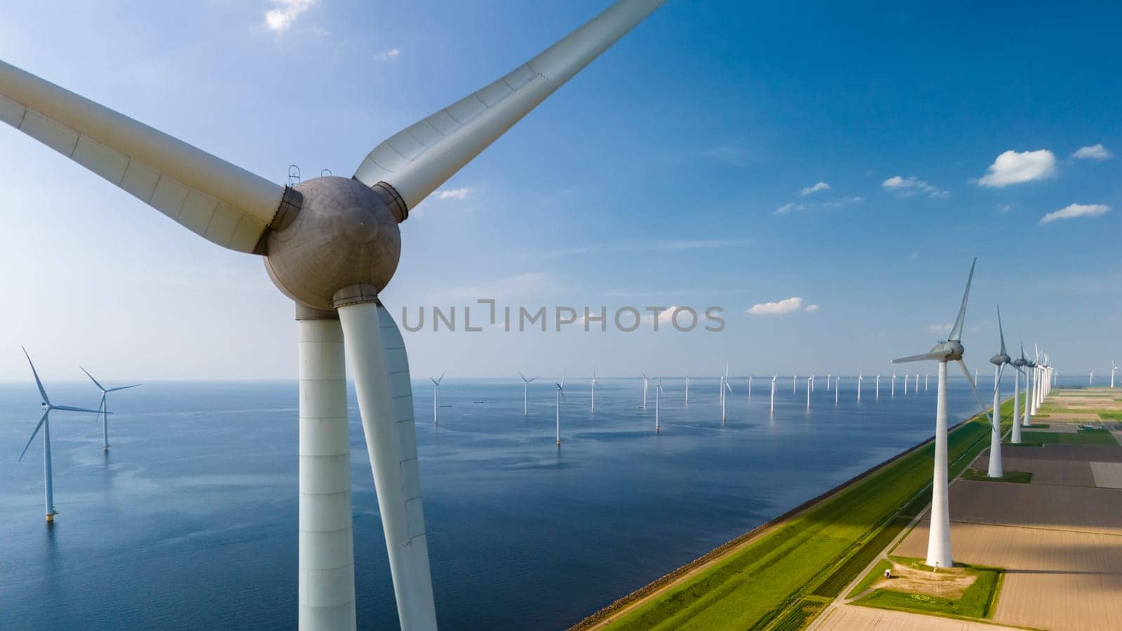 Aerial view of windmill turbines spinning gracefully in a wind farm near the ocean in the Netherlands Flevoland.