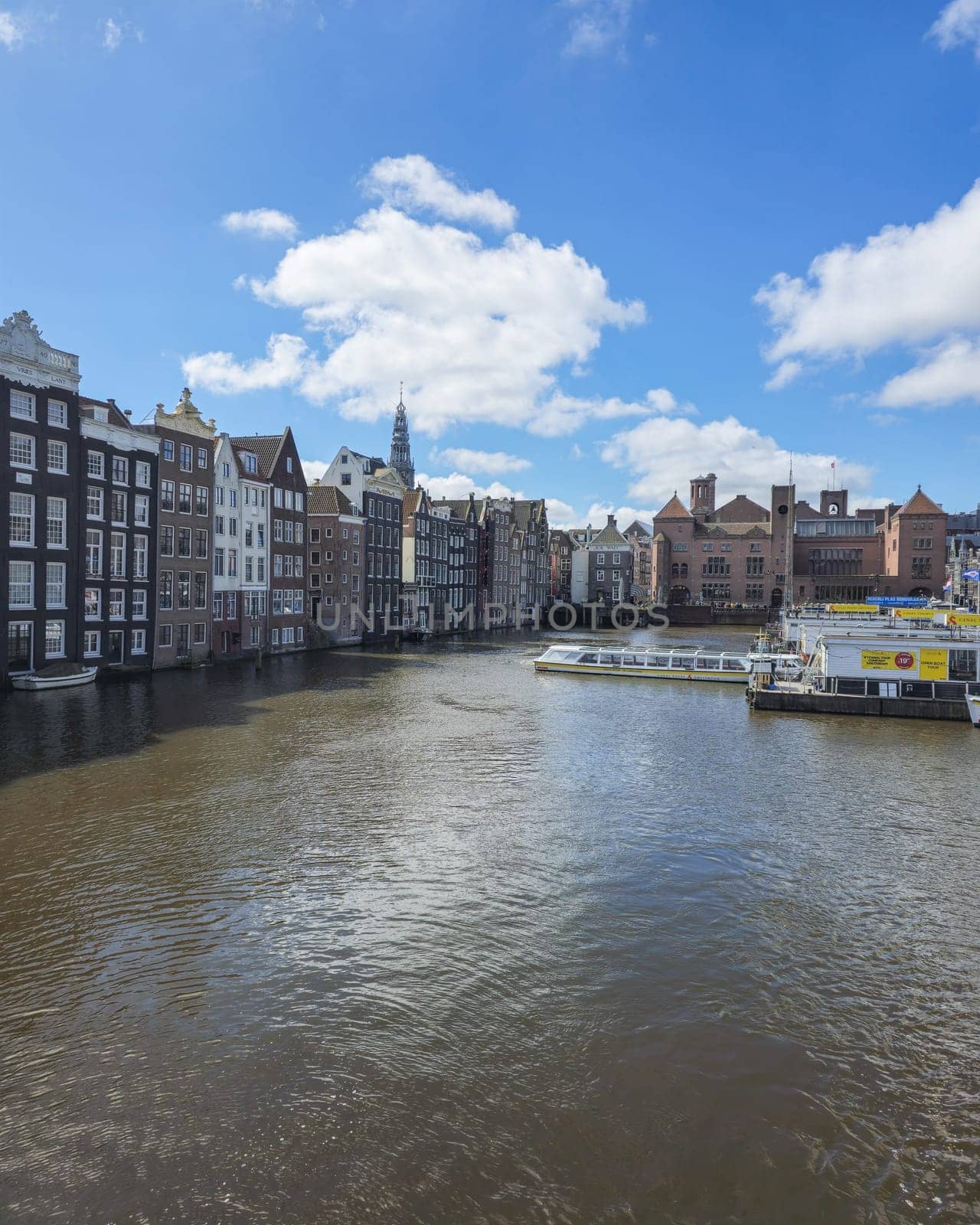 Amsterdam Netherlands 21 April 2024, A picturesque scene of a river flowing gracefully through a bustling city, with tall skyscrapers lining its banks under the clear sky.