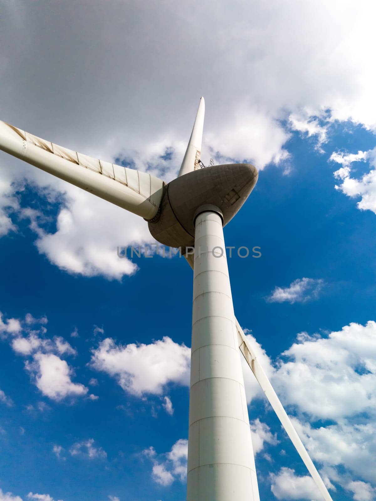 A wind turbine gracefully spins against a vibrant blue sky backdrop in Flevoland, Netherlands.