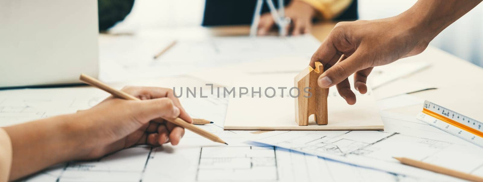 Professional architect team discussion about architectural project on meeting table with blueprint and wooden block scatter around at modern office. Closeup. Focus on hand. Delineation.