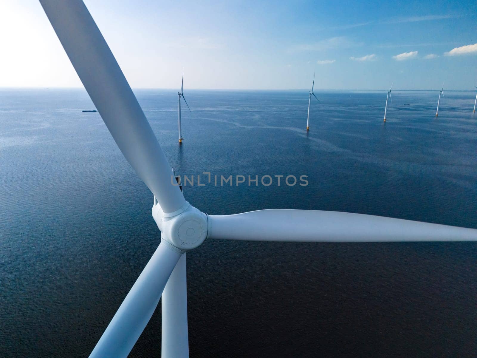 Windmills stand tall in the middle of the ocean, generating clean energy for the Netherlands from the strong sea breezes.