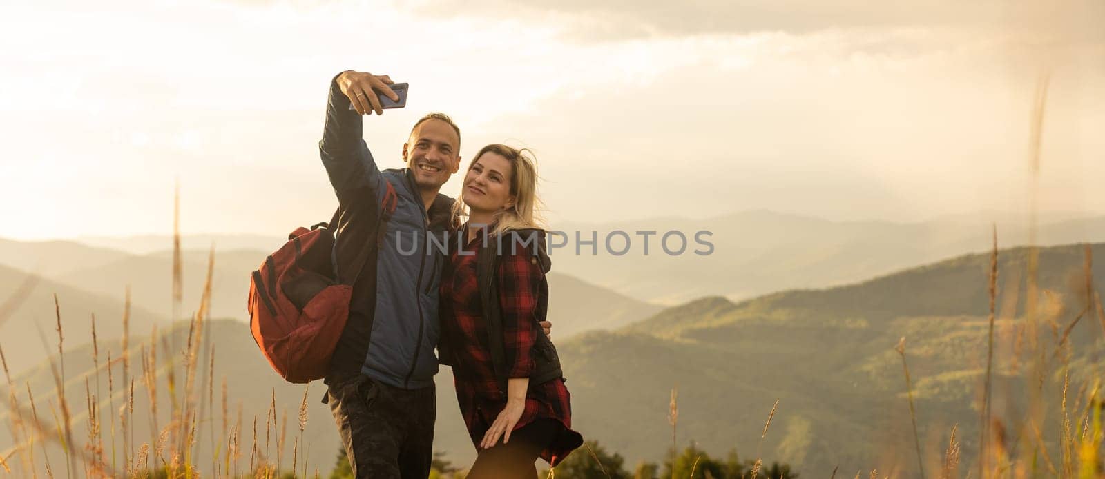 Happy traveler young couple resting in the mountains at sunset in spring or summer season