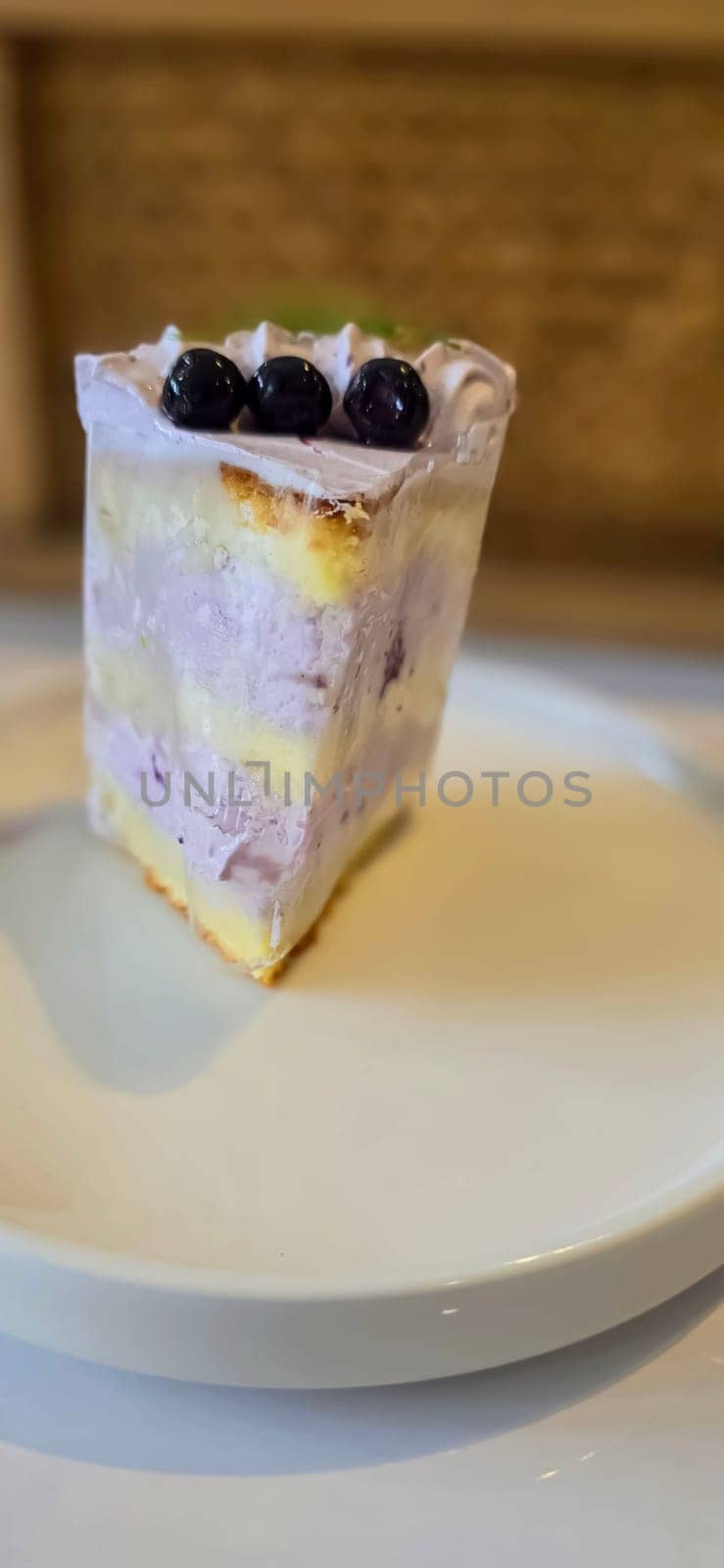 slice of blueberry cake decorated with fresh berries on white plate, delicious layered cake, top view by antoksena