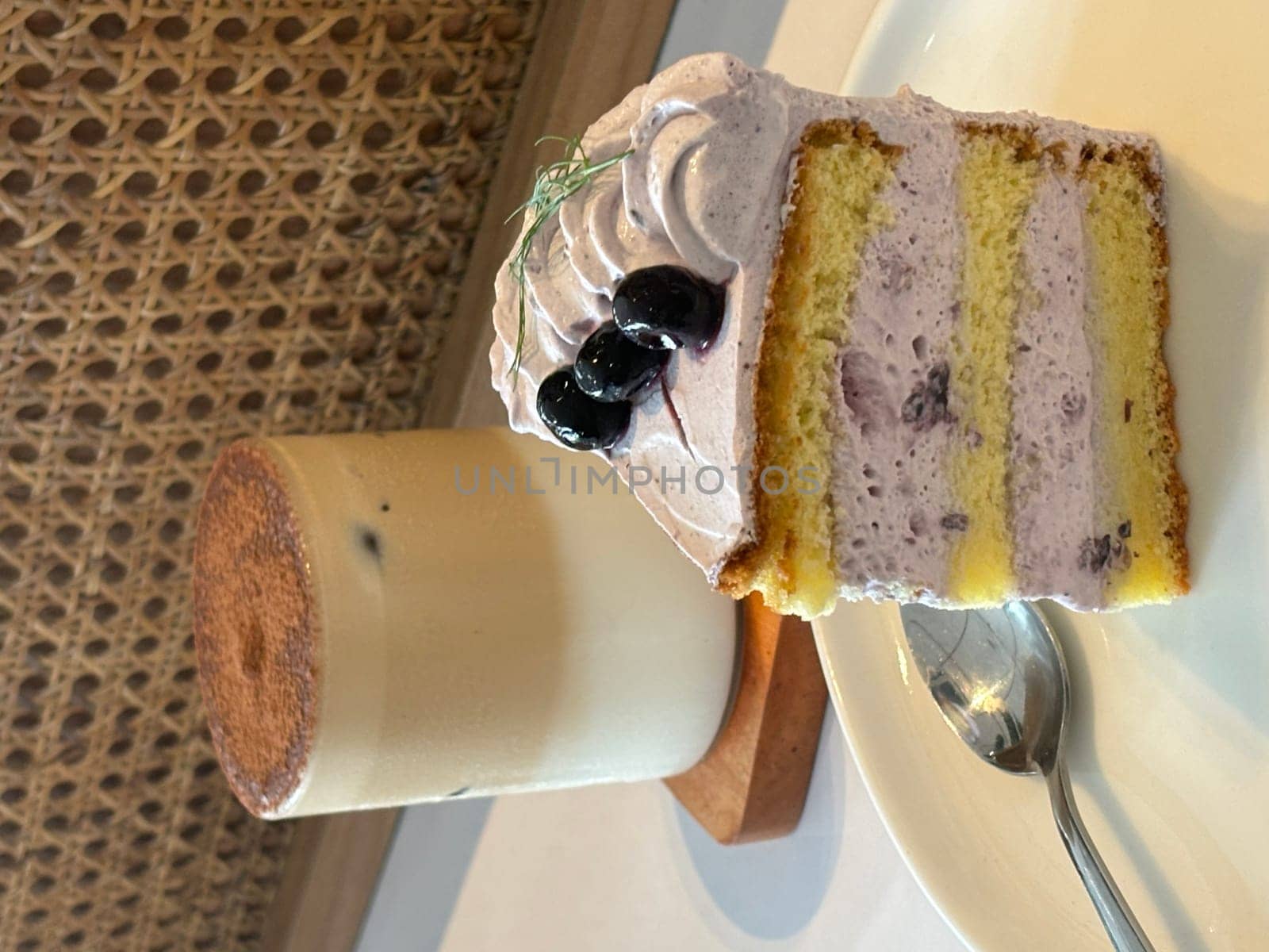 slice of blueberry cake decorated with fresh berries on white plate, delicious layered cake, top view in the cafe