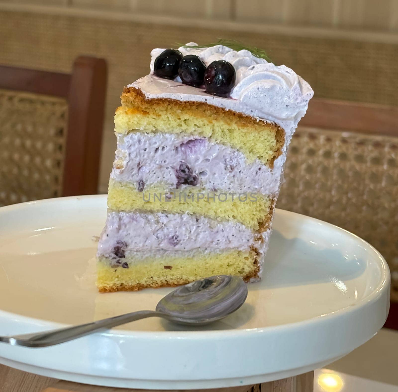 slice of blueberry cake decorated with fresh berries on white plate, delicious layered cake, top view in the cafe