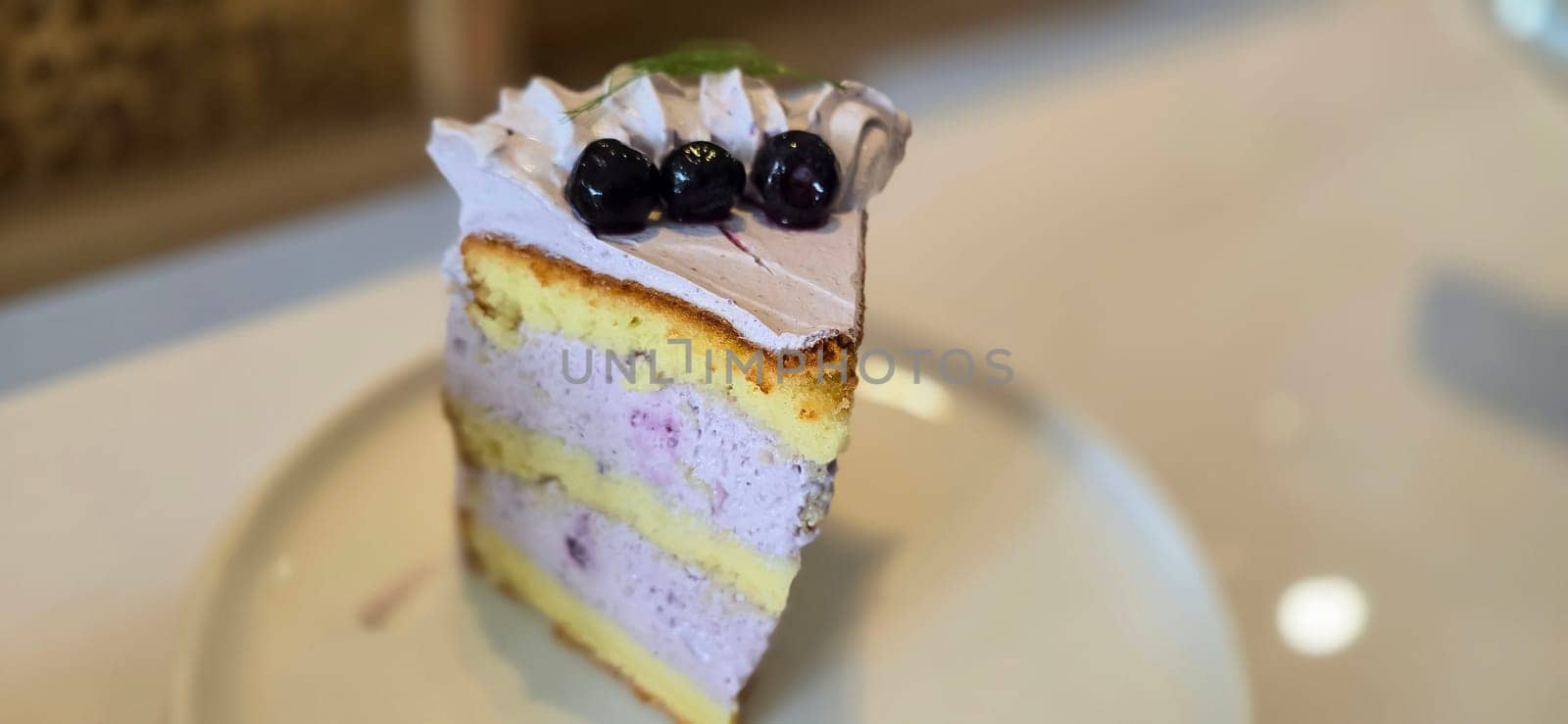 slice of blueberry cake decorated with fresh berries on white plate, delicious layered cake, top view in the cafe