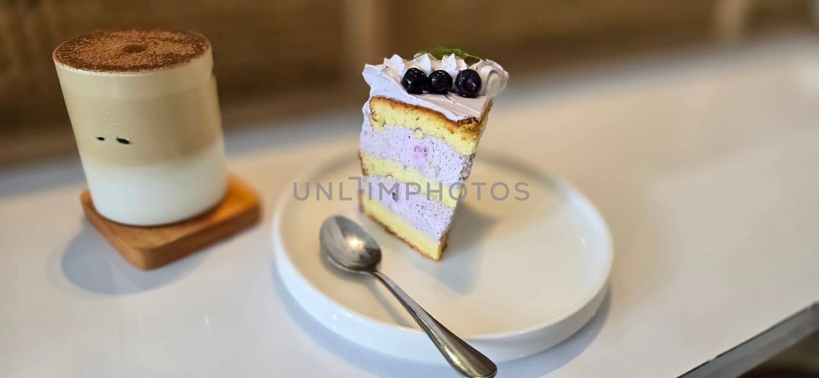 slice of blueberry cake decorated with fresh berries on white plate, delicious layered cake, top view in the cafe