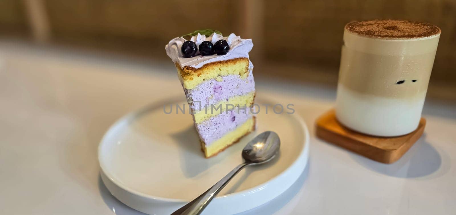 slice of blueberry cake decorated with fresh berries on white plate, delicious layered cake, top view in the cafe