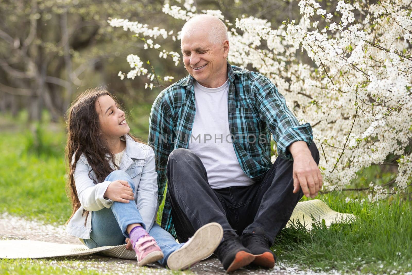 Smiling child hugging her happy grandfather - outdoor in nature