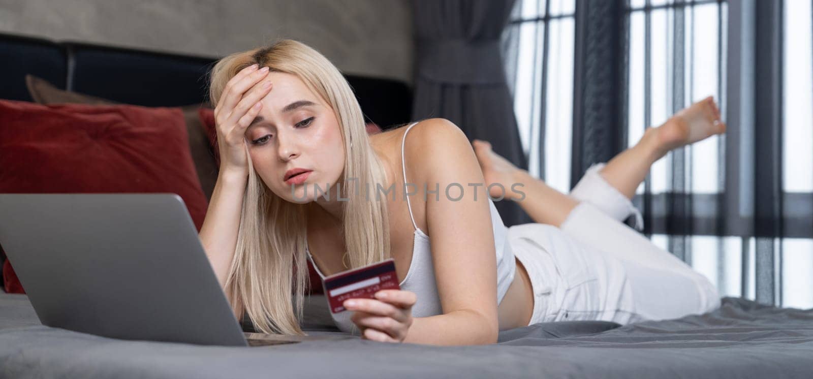 Stress worried young woman sit at table, as she pay bills online with credit card from financial debt problem, monthly expense and credit card debt. Over spending money problem. Panorama Blithe