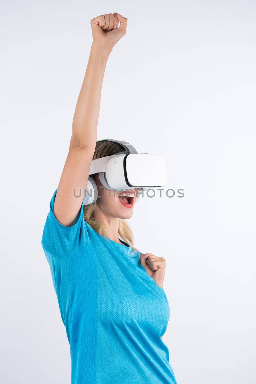 Caucasian happy girl wearing VR glasses and making winner gesture. Skilled woman celebrate while winning game by using VR headsets and standing at pink background. Technology innovation. Contraption.
