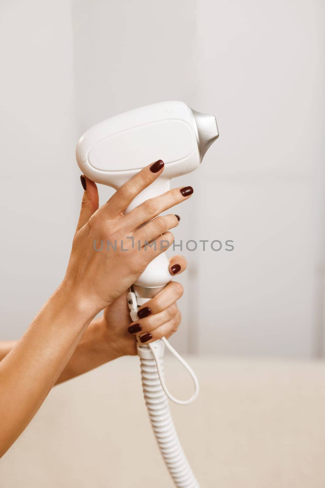 Body Care. Underarm Laser Hair Removal. Woman tunes a laser hair removal machine. She holds a working part of the epilator in her hands and poses for a photo.
