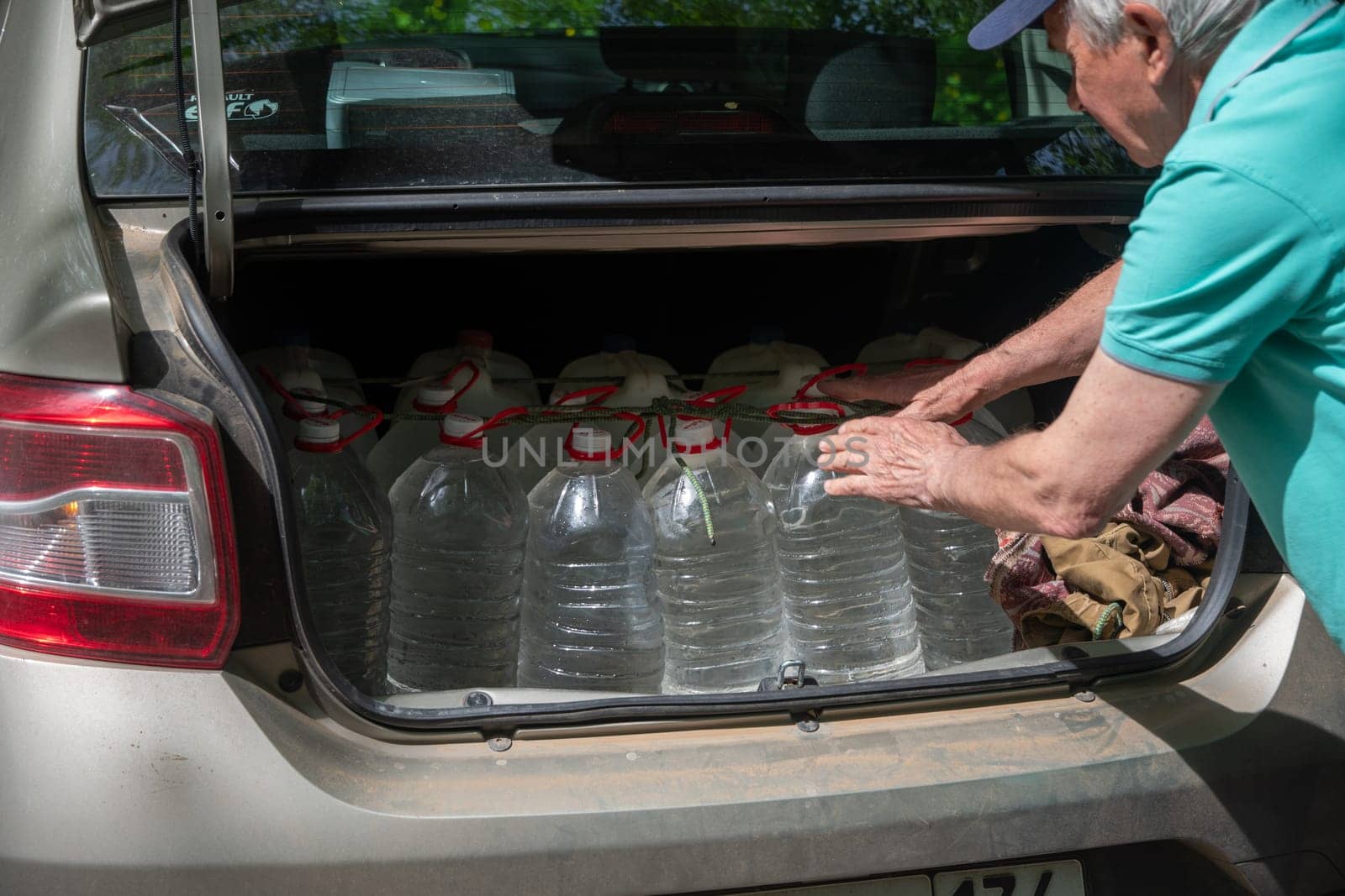 male volunteer loads many five-liter bottles of clean drinking water into the trunk to help victims of a natural disaster. High quality photo