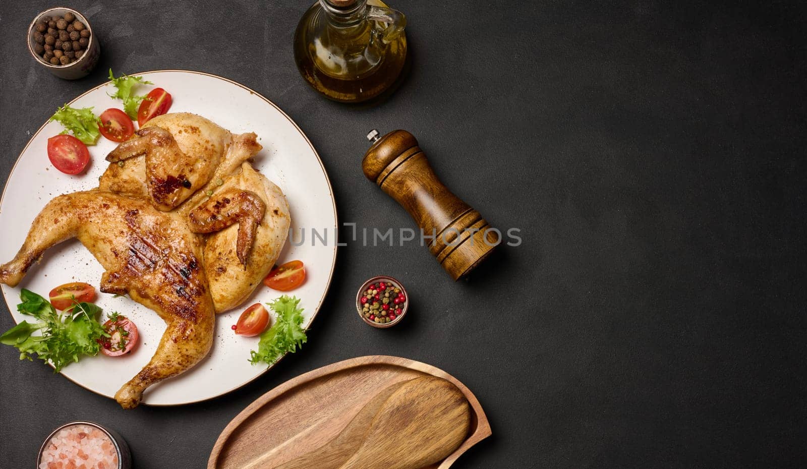 Whole fried chicken with spices in a white round plate on the table, top view. Copy space