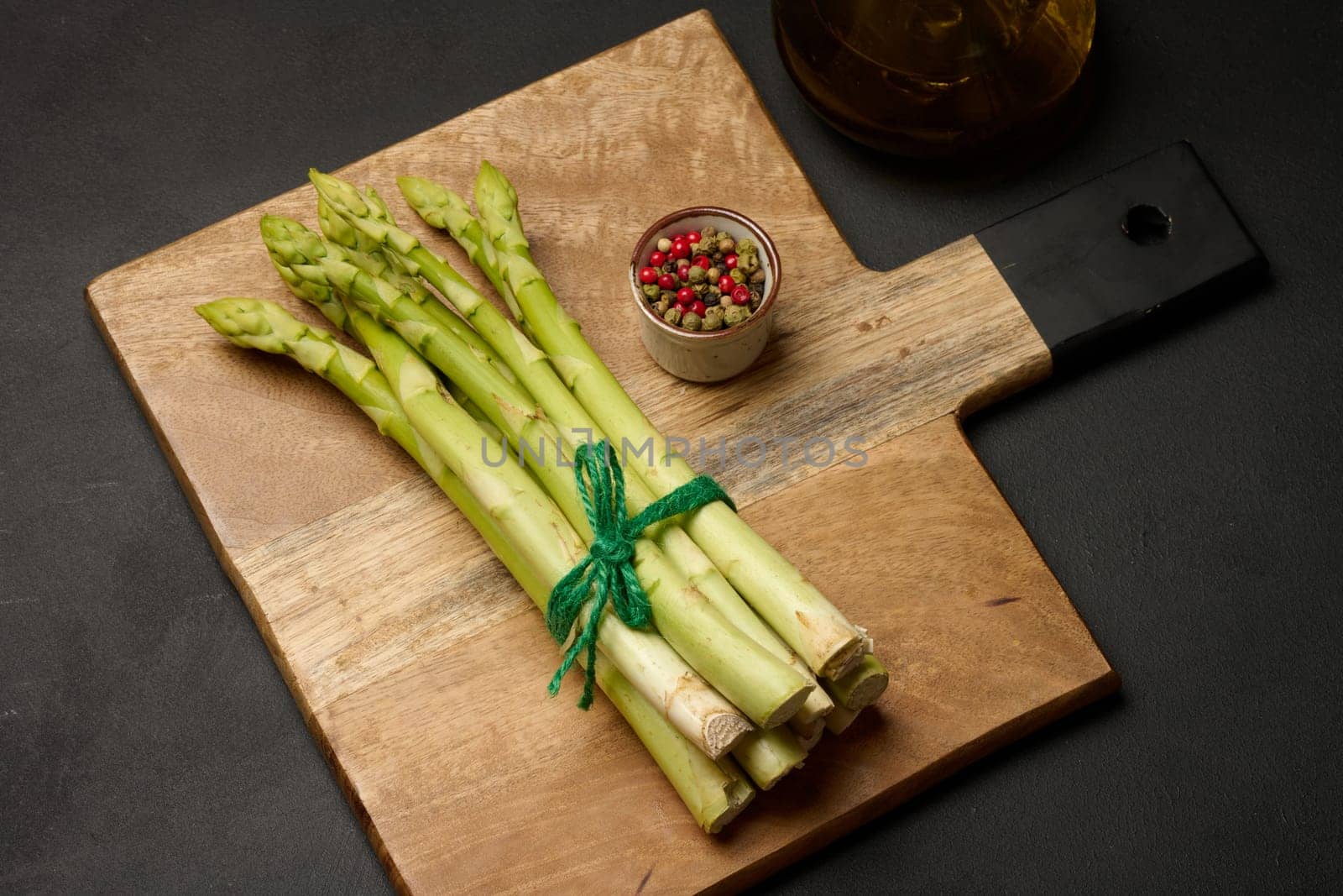 Fresh green asparagus sprouts on a black wooden background. View from above by ndanko