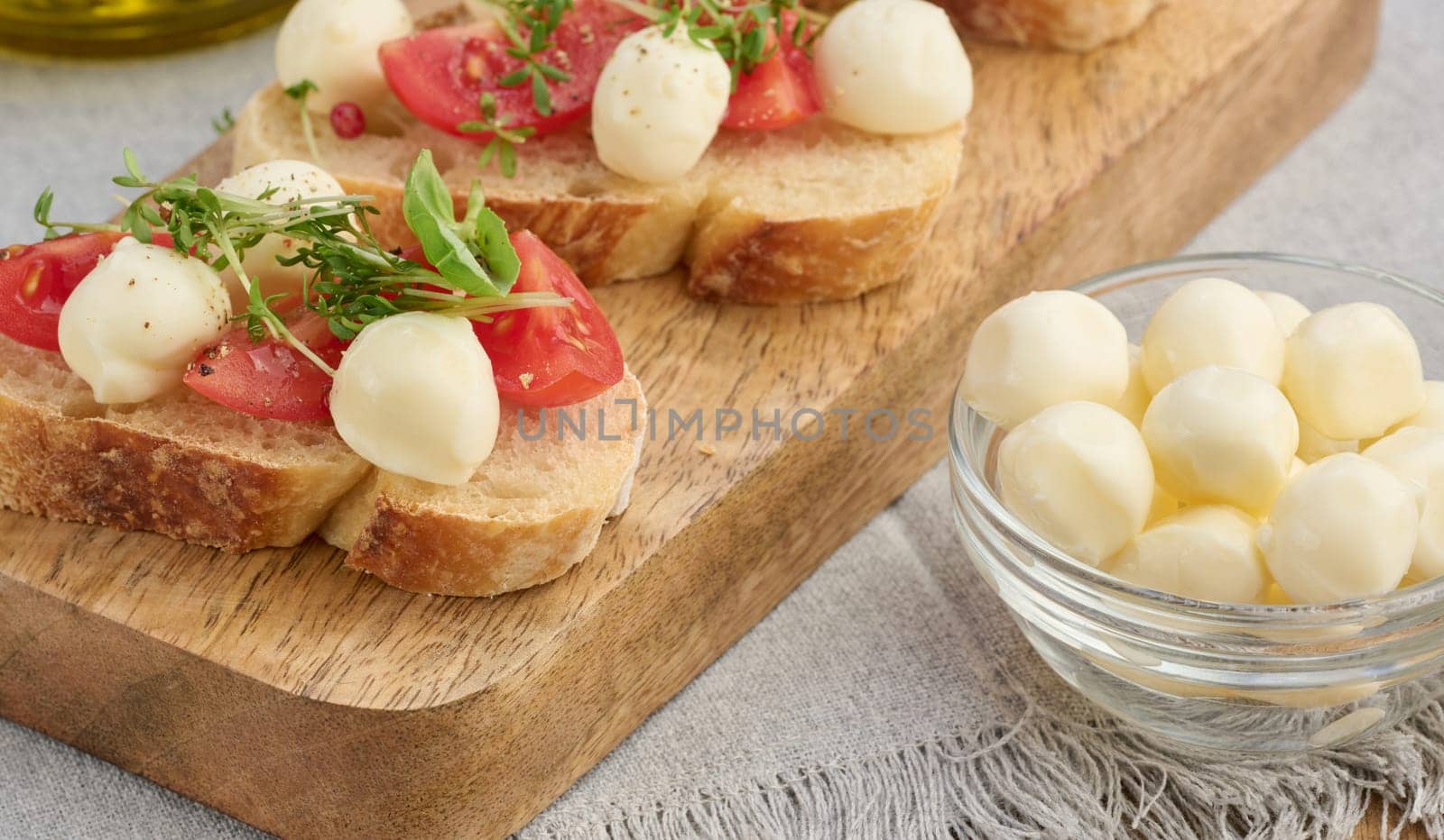 Round mozzarella, cherry tomatoes and microgreens on a piece of white bread, a healthy sandwich, close up
