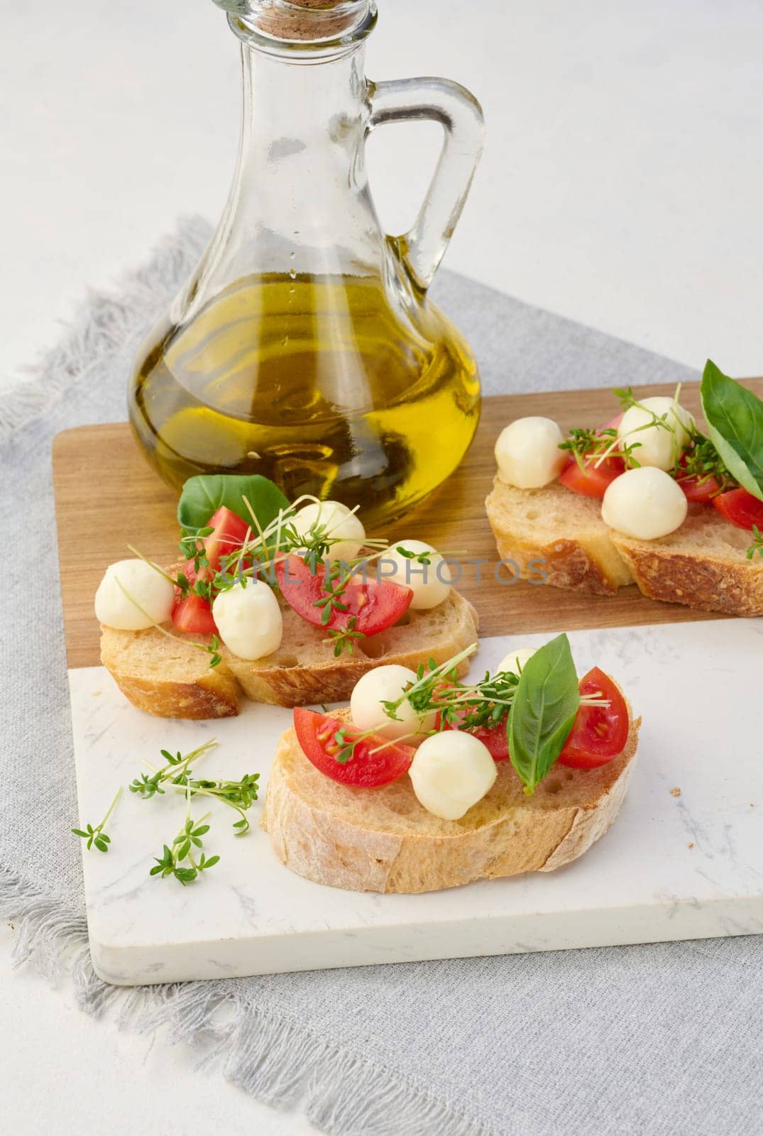 Round mozzarella, cherry tomatoes and microgreens on a piece of white bread, top view