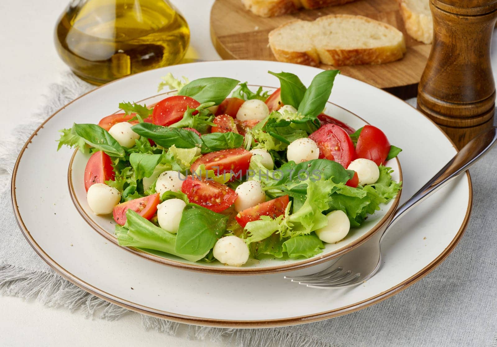 Salad with mozzarella, cherry tomatoes and green lettuce in a white round plate  by ndanko
