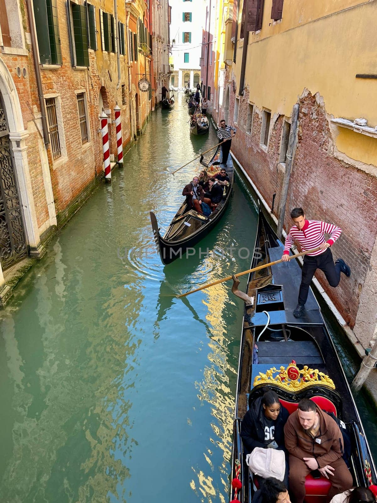 Italy, Venice, April 25, 2024, Gondoliers on gondolas carry tourists by MilaLazo