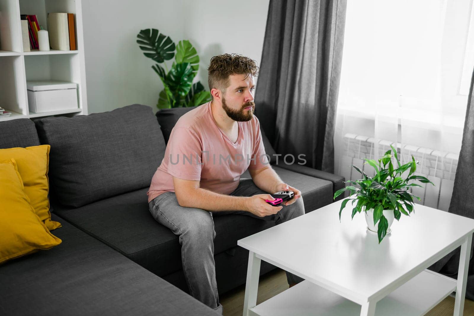 Man playing videogames in living room sitting on sofa. by Satura86