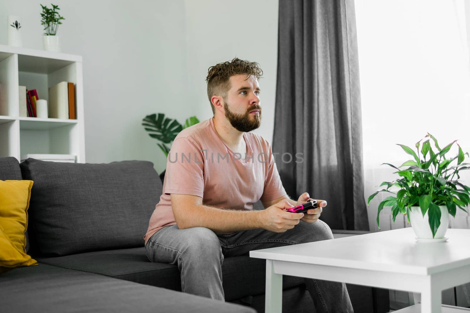 Man playing videogames in living room sitting on sofa. by Satura86