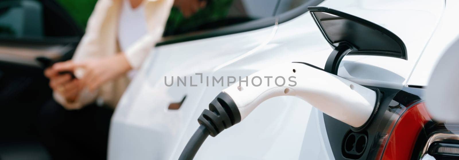 Young woman use smartphone to pay for electricity for EV car. Expedient by biancoblue